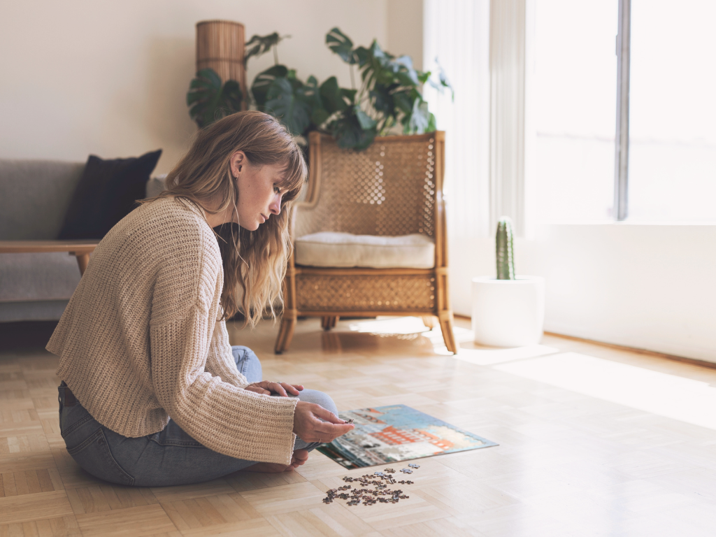 Woman sitting on wooden floor assembling a puzzle